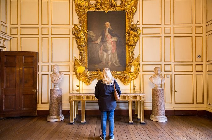 A panelled state room at Warwick Castle hung with portraits above marble busts