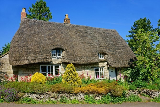 A thatched, flower-fronted cottage in the countryside near Stratford-upon-Avon