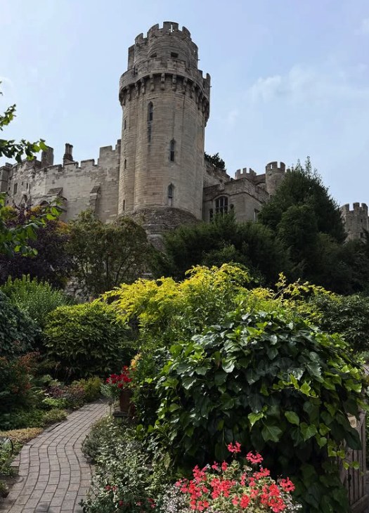 Planting in the Warwick Castle gardens with a tower rising behind