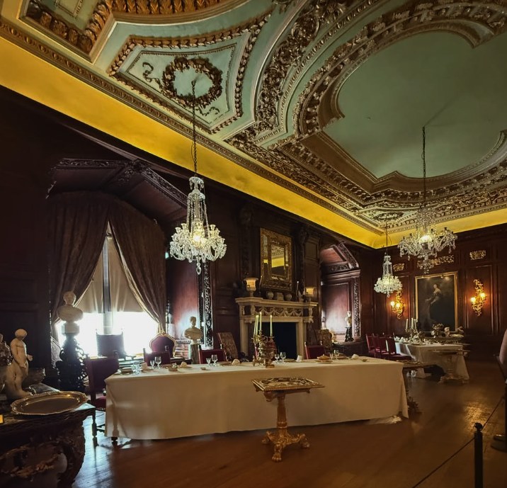 The State Dining Room at Warwick Castle, laid and lit under its gilded ceiling