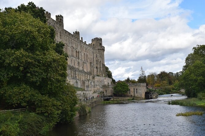 Warwick Castle seen along the River Avon between the trees